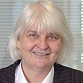 Sie sehen ein Portrait von Professorin Hooffacker, die vor einem hellen Hintergrund steht.