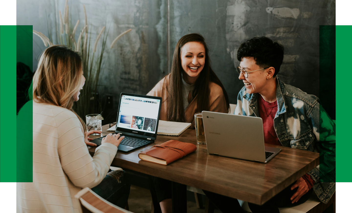 Drei Frauen sitzen zusammen am Tisch und sind miteinander im Gespräch. Vor ihnen stehen Laptops, Bücher und Getränke.