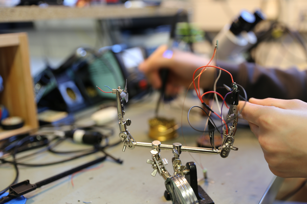 Nahaufnahme einer Hand, die an einem Minirotor und Kabeln arbeitet und Drähte löten will