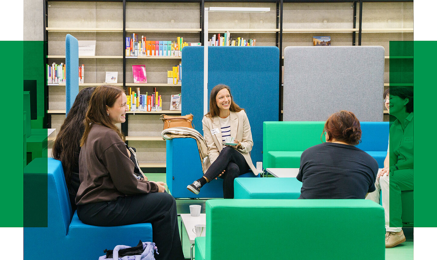 Foto vom FSN Frühstück 2024 Das Foto zeigt fünf Personen, die auf grünen und blauen Sofas in der Bibliothek der HTWK sitzen und netzwerken,