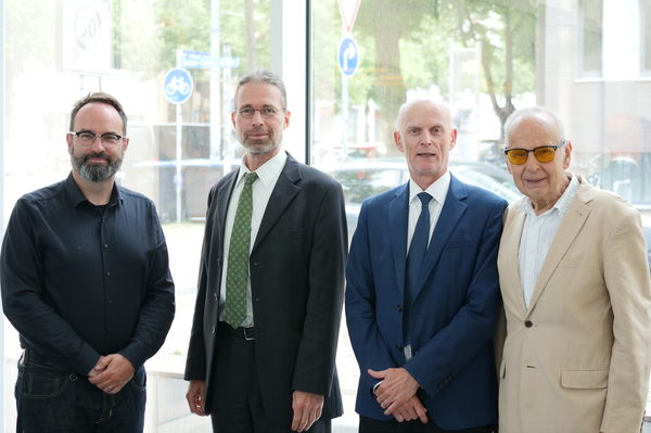 Gruppenfoto, alle Personen schauen zur Kamera, im Hintergrund eine Glasfront