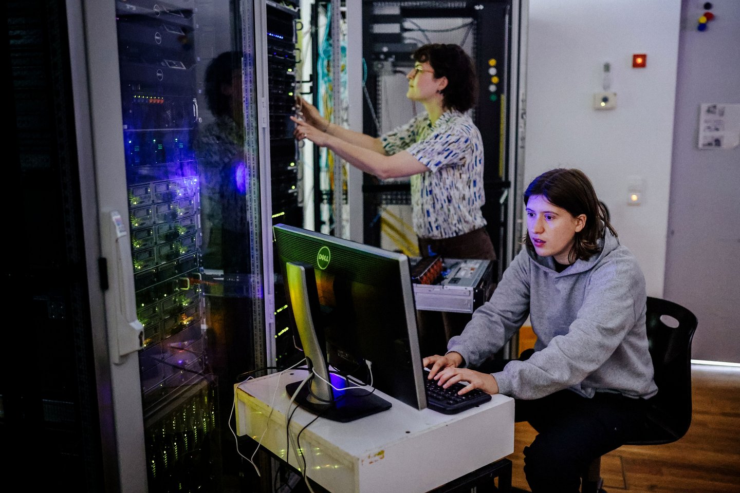 Zwei Personen befinden sich in einem Serverraum und arbeiten.