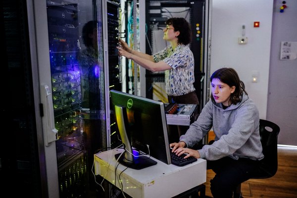 Zwei Personen befinden sich in einem Serverraum und arbeiten.