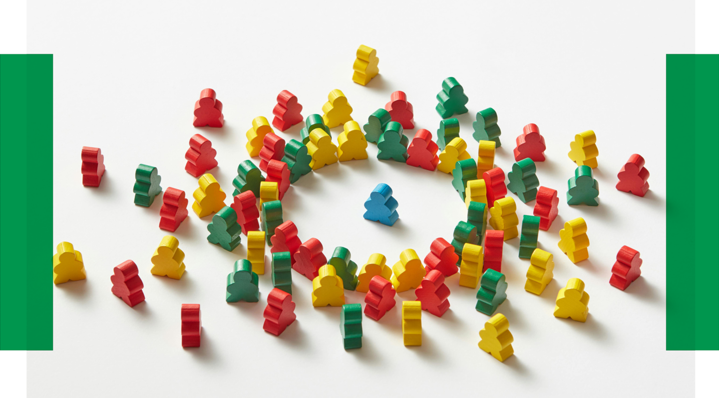 Gruppen-Mentoring mit Mentorin Buntes Spielzeug, das aussieht wie kleine Personen, liegt im Kreis beieinander. Eine Spielzeugfigur steht in der Mitte des Kreises.