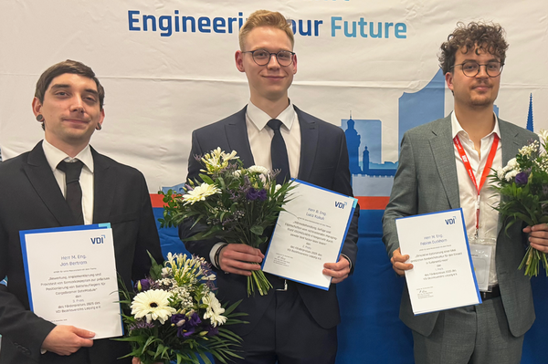 Portraitfoto der drei Preisträger mit Urkunde und Blumen in der Hand