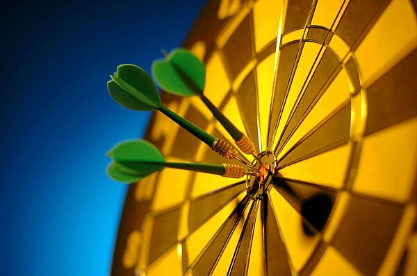 In the picture, you can see a yellow-brown dartboard with four darts sticking in the center.