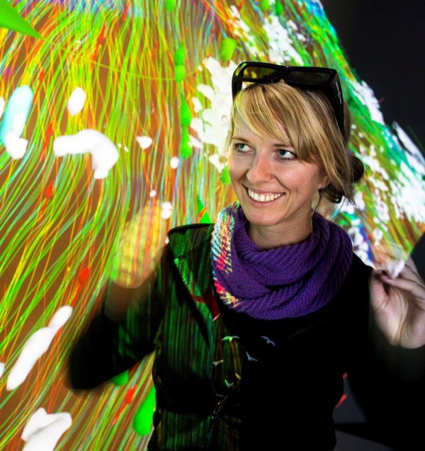 Prof.in Dr.in Carolin Helbig, Alumna der HTWK Leipzig Auf dem Bild steht Prof.in Dr.in Carolin Helbig vor einem farbigen Lichtervorhang